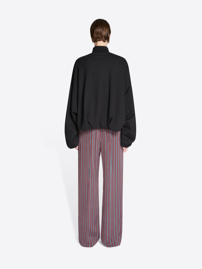 Person wearing a black jacket and striped pants on a white background - Dries Van Noten