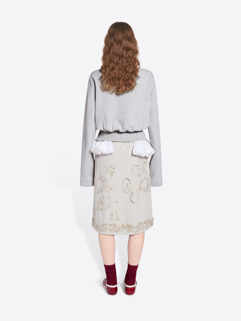 Person wearing a light gray sweater over a white top and beige skirt on a white background - Dries Van Noten