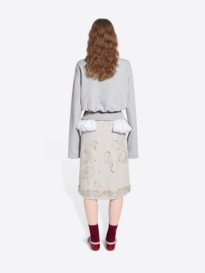 Person wearing a light gray sweater over a white top and beige skirt on a white background - Dries Van Noten