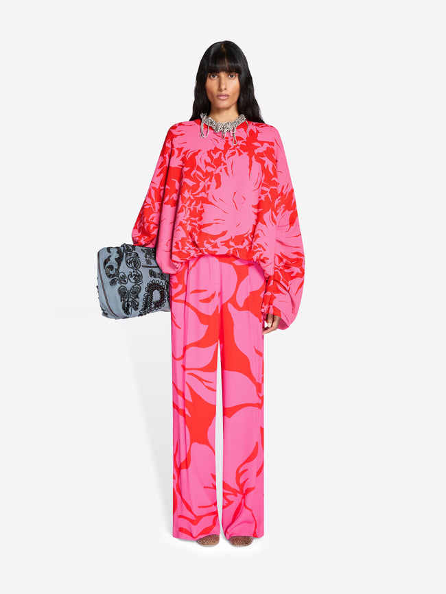 Person wearing a bright pink floral outfit with a gray clutch against a white background - Dries Van Noten