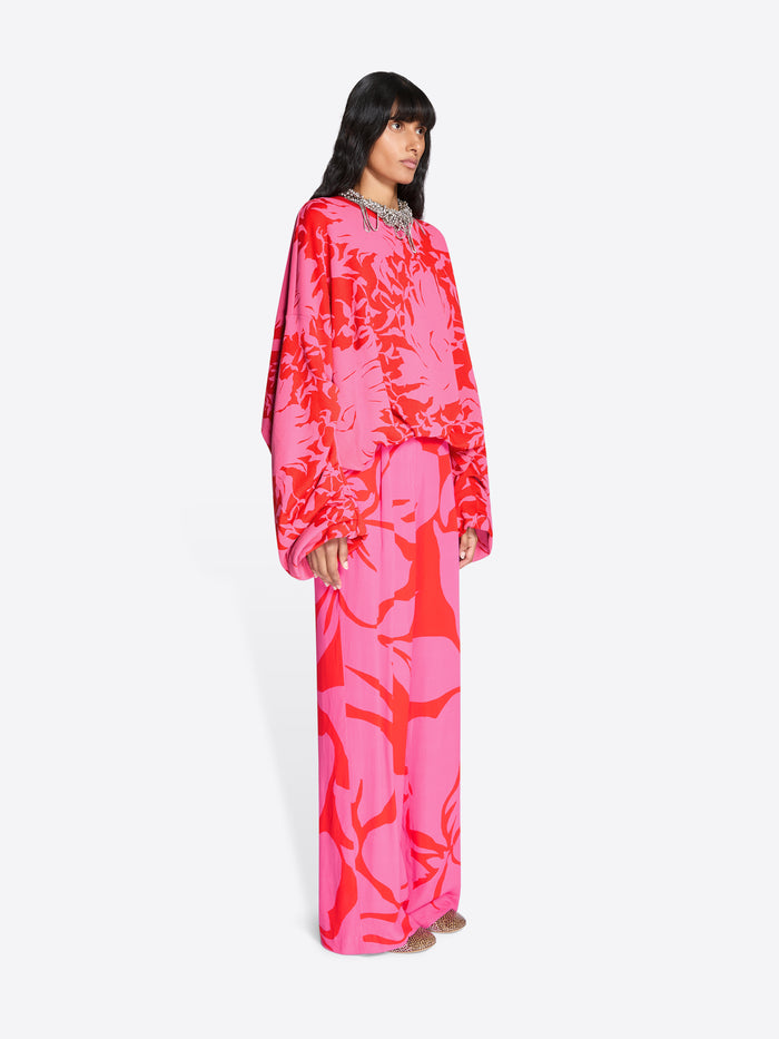 Woman wearing a vibrant pink and red patterned set on a white background - Dries Van Noten