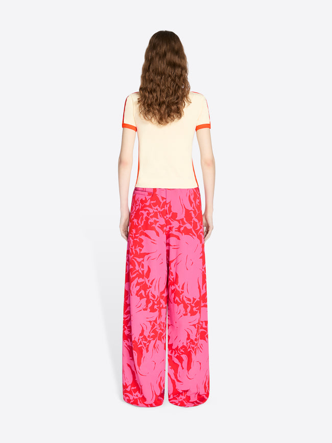 Person wearing a yellow top with red trim and pink floral pants on a white background - Dries Van Noten