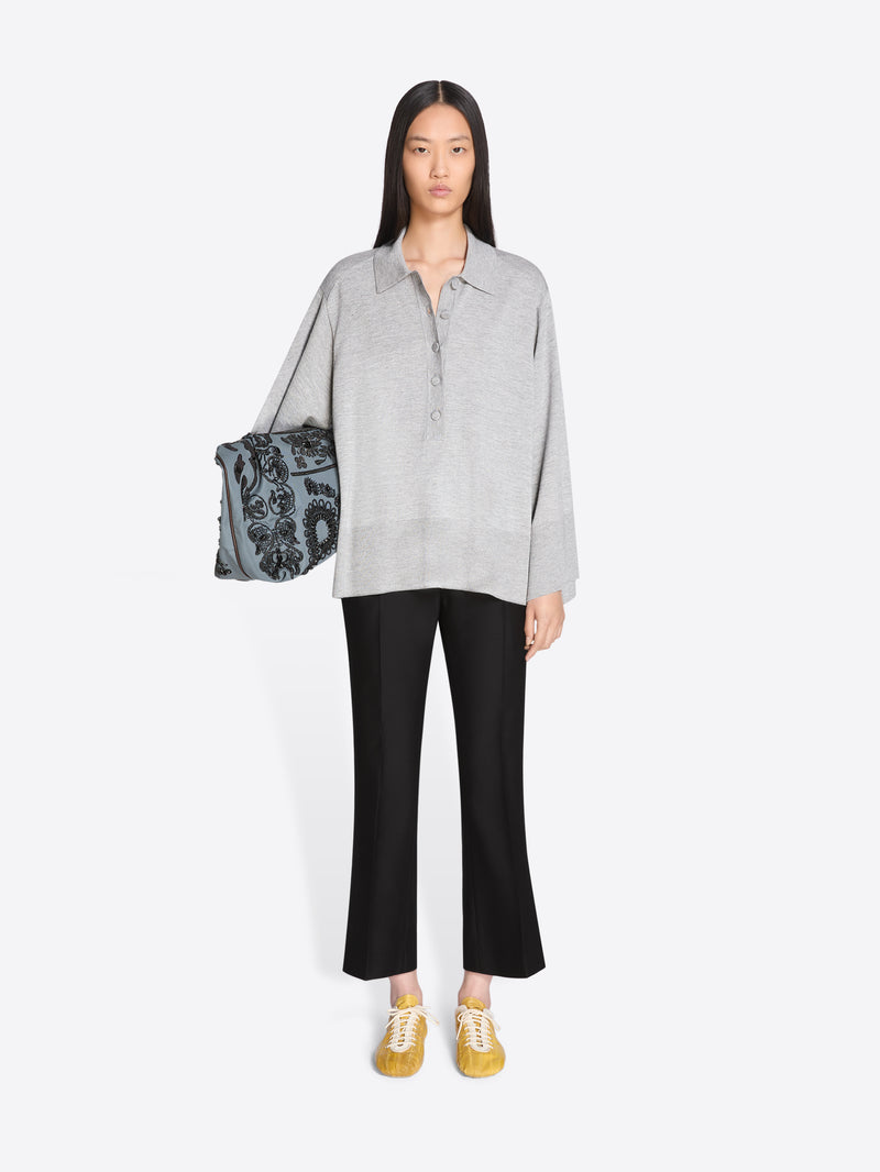 Woman holding a patterned bag, wearing a gray shirt and black pants on a white background - Dries Van Noten