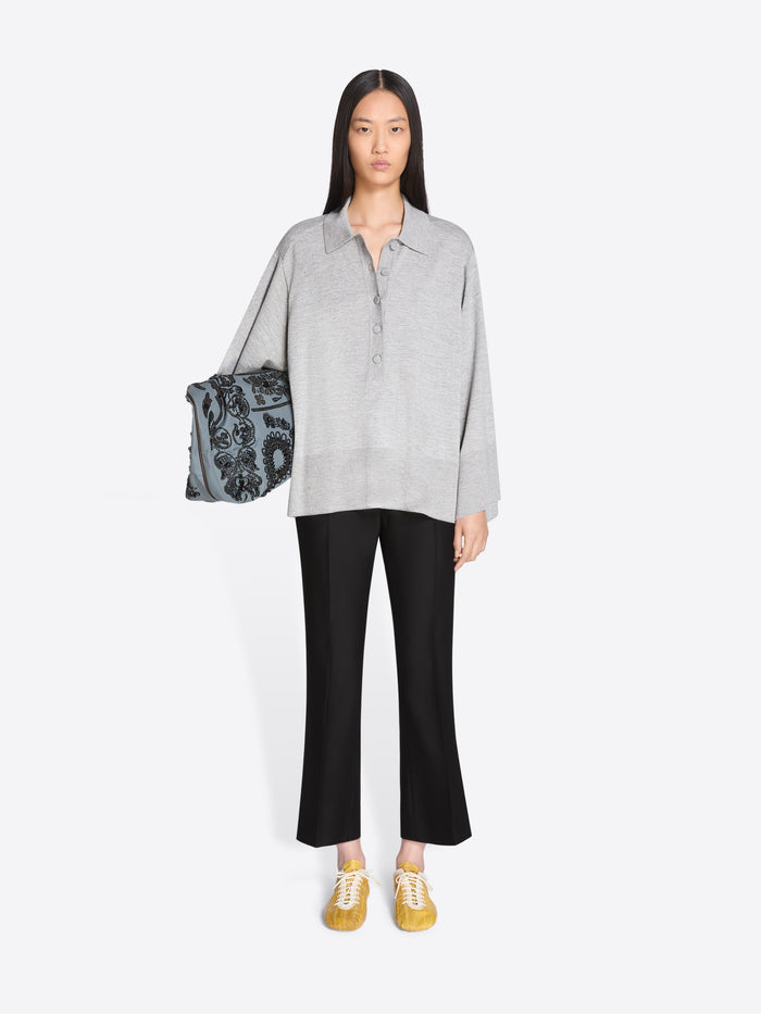 Woman holding a patterned bag, wearing a gray shirt and black pants on a white background - Dries Van Noten