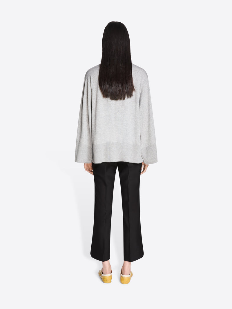 Person wearing a light gray top and black pants on a white background - Dries Van Noten