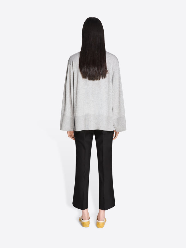 Person wearing a light gray top and black pants on a white background - Dries Van Noten