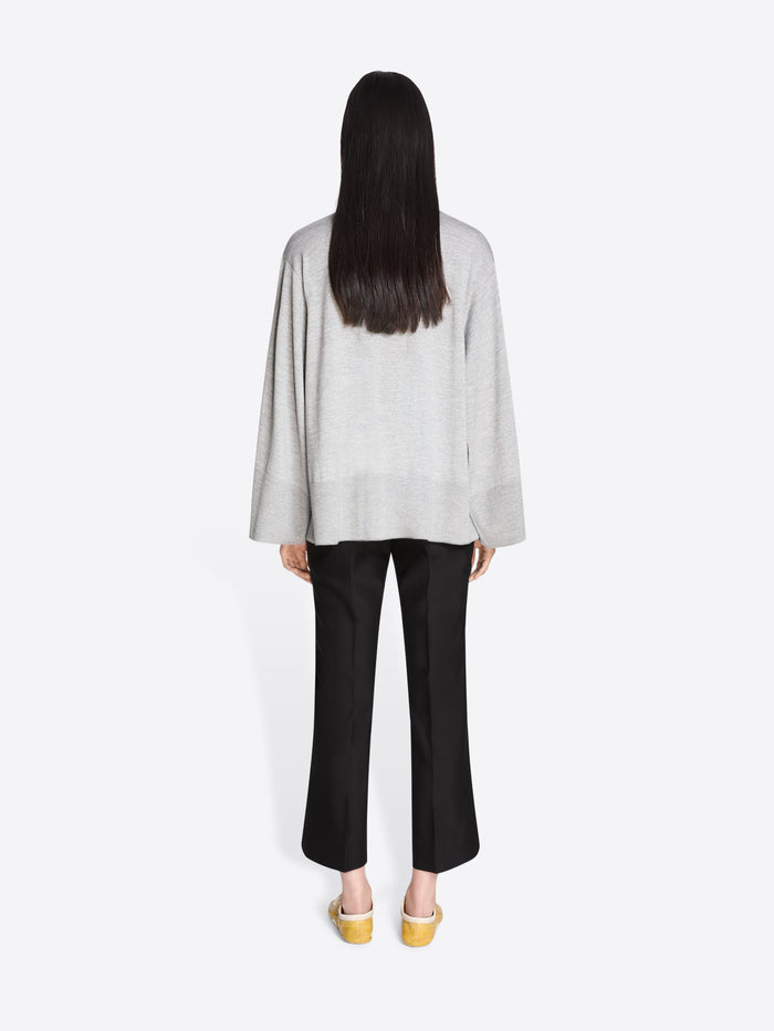 Person wearing a light gray top and black pants on a white background - Dries Van Noten