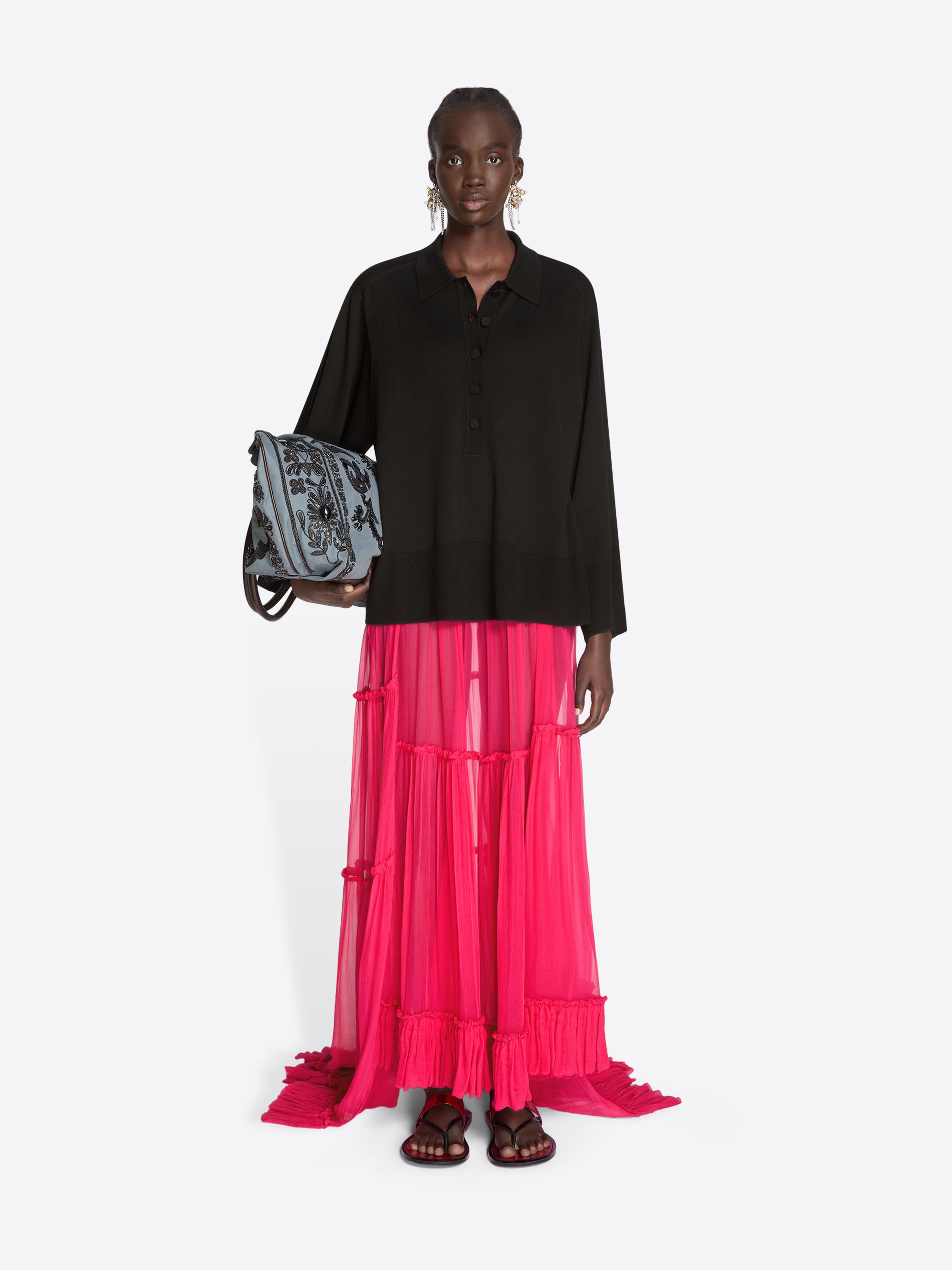Woman wearing a black top and pink skirt holding a patterned bag on a white background - Dries Van Noten
