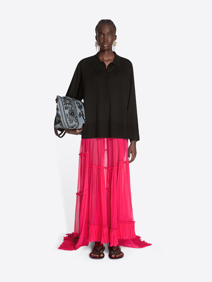 Woman wearing a black top and pink skirt holding a patterned bag on a white background - Dries Van Noten