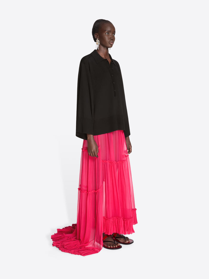 Model wearing a black top and bright pink layered skirt on a white background - Dries Van Noten