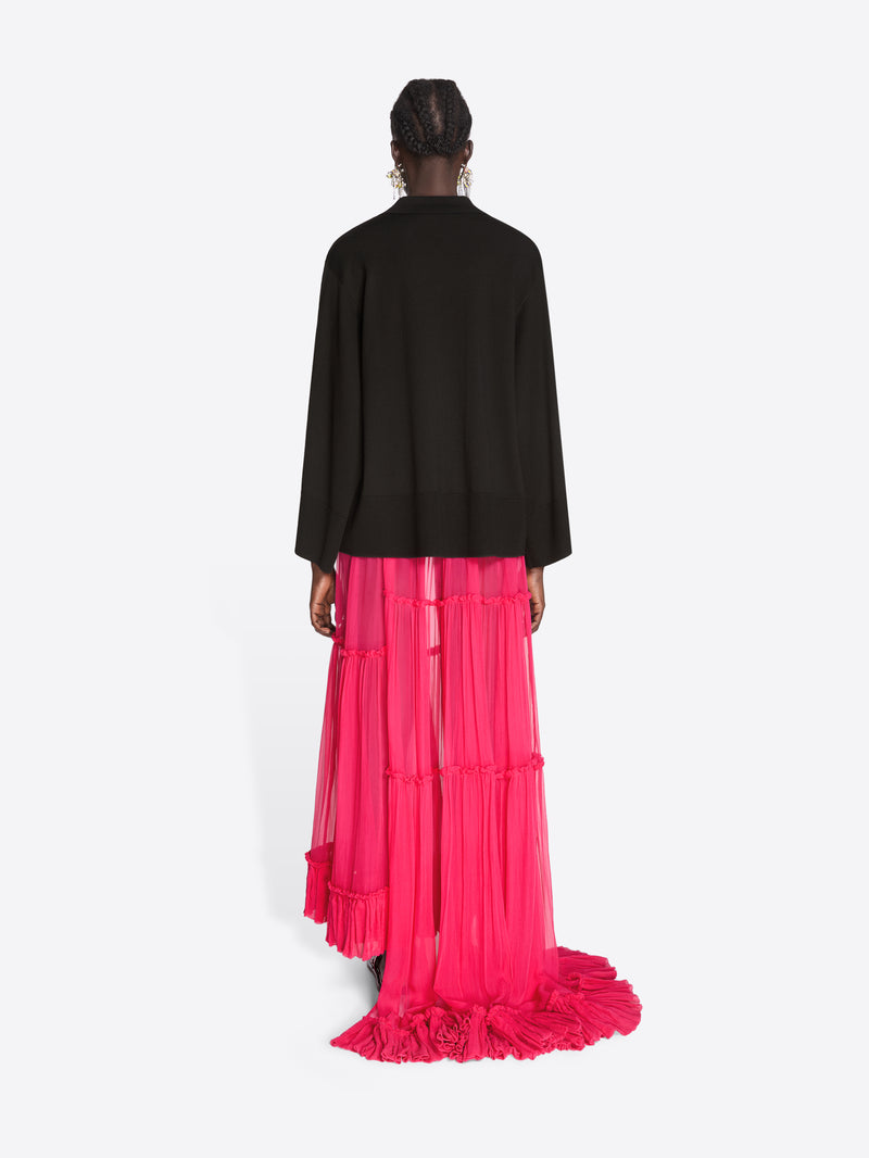 Person wearing a black top and pink ruffled skirt on a white background - Dries Van Noten