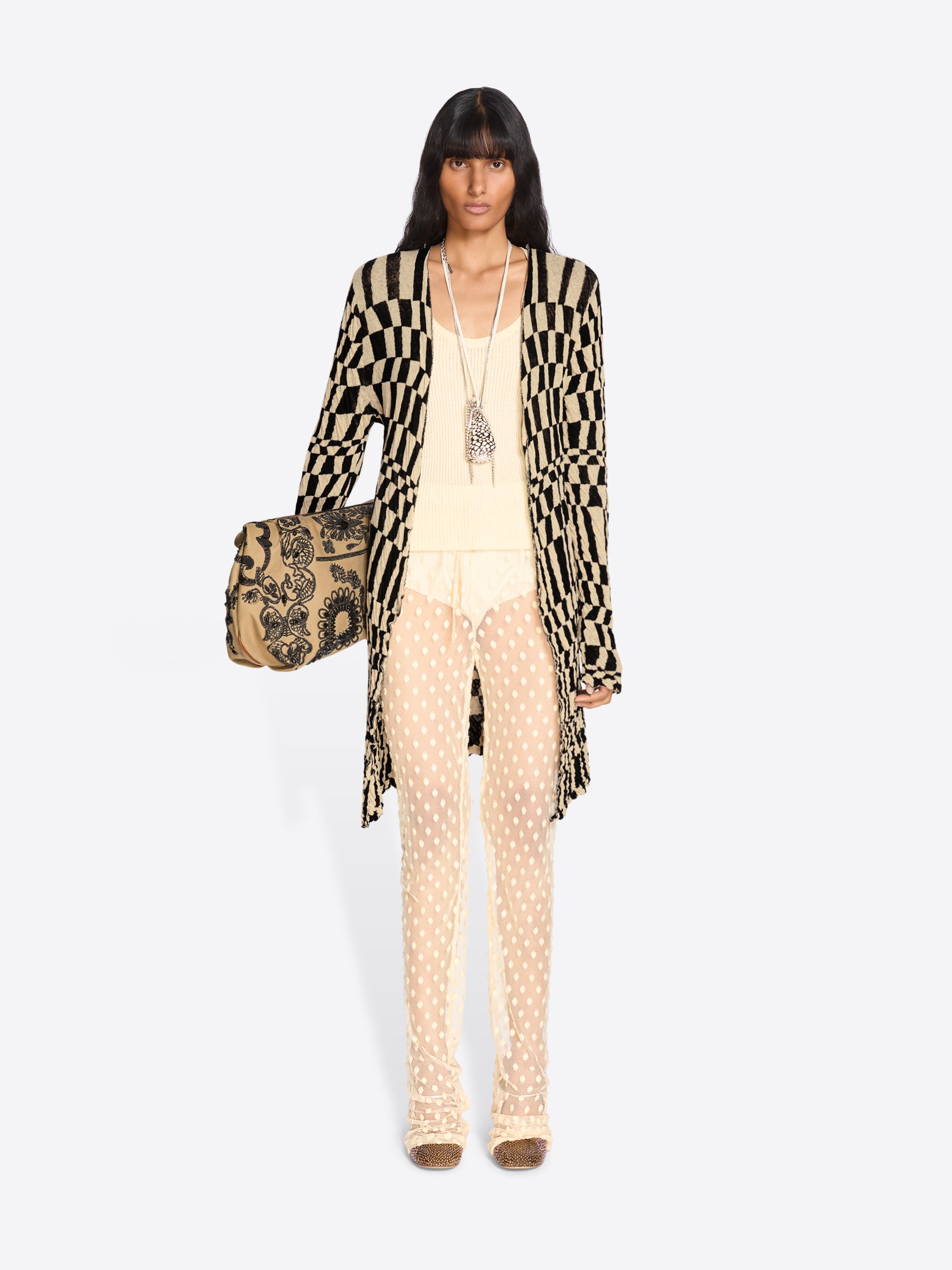 Woman wearing a patterned outfit with a beige handbag on a white background - Dries Van Noten
