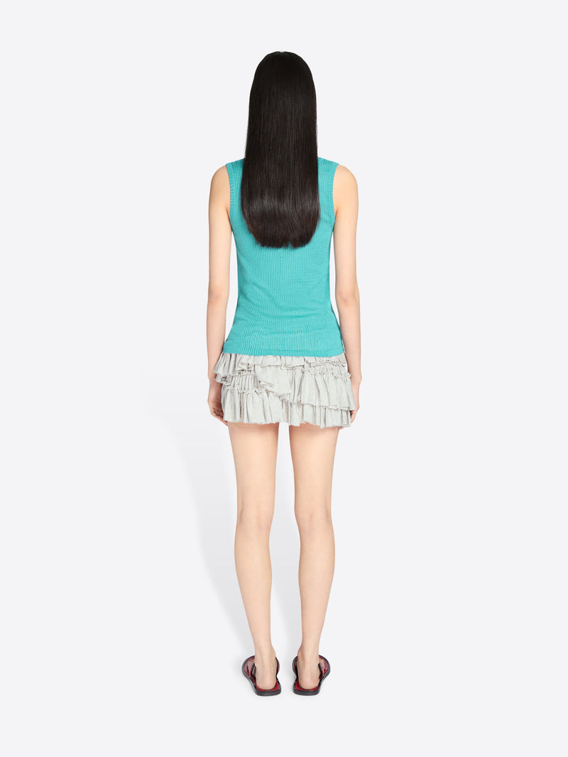 Person wearing a turquoise sleeveless top and ruffled skirt on a white background - Dries Van Noten