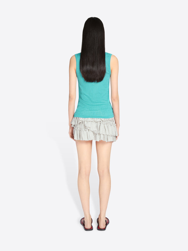 Person wearing a turquoise sleeveless top and ruffled skirt on a white background - Dries Van Noten