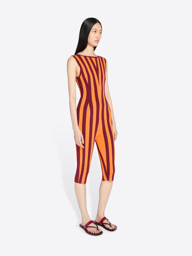 Woman wearing a sleeveless orange and red striped jumpsuit on a white background - Dries Van Noten