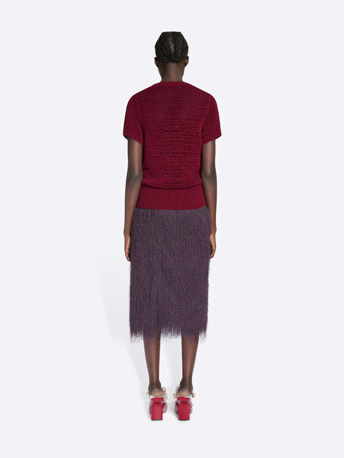 Person wearing a red top and dark purple skirt on a white background - Dries Van Noten