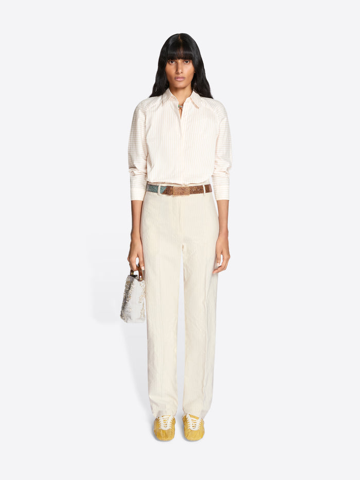Woman wearing a white outfit with a belt and gold shoes on a white background - Dries Van Noten