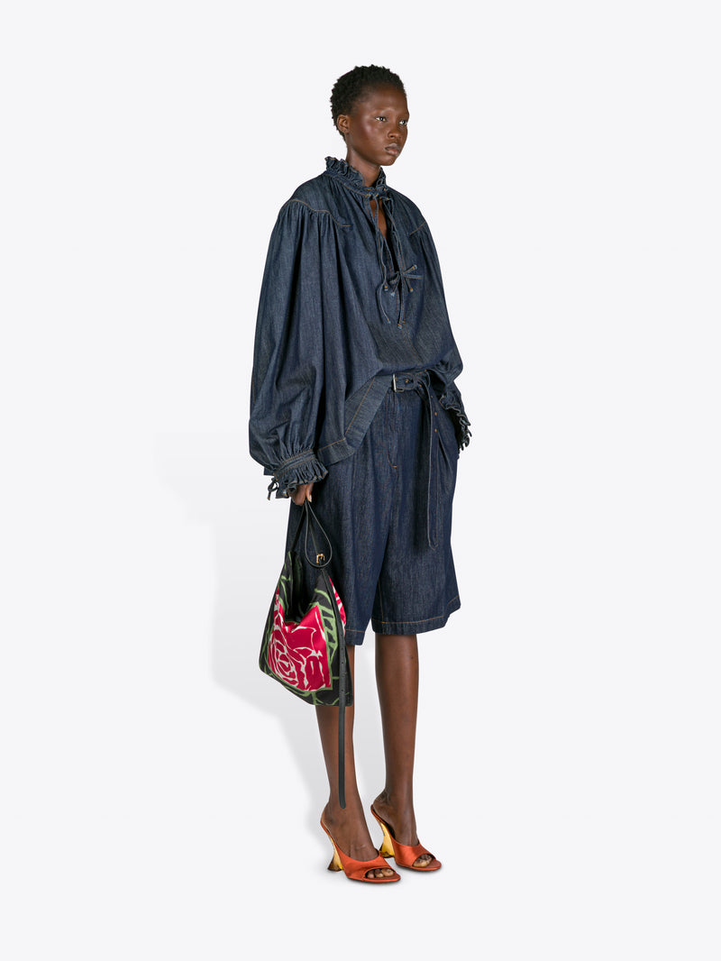 Woman wearing a dark denim outfit holding a colorful handbag on a white background - Dries Van Noten