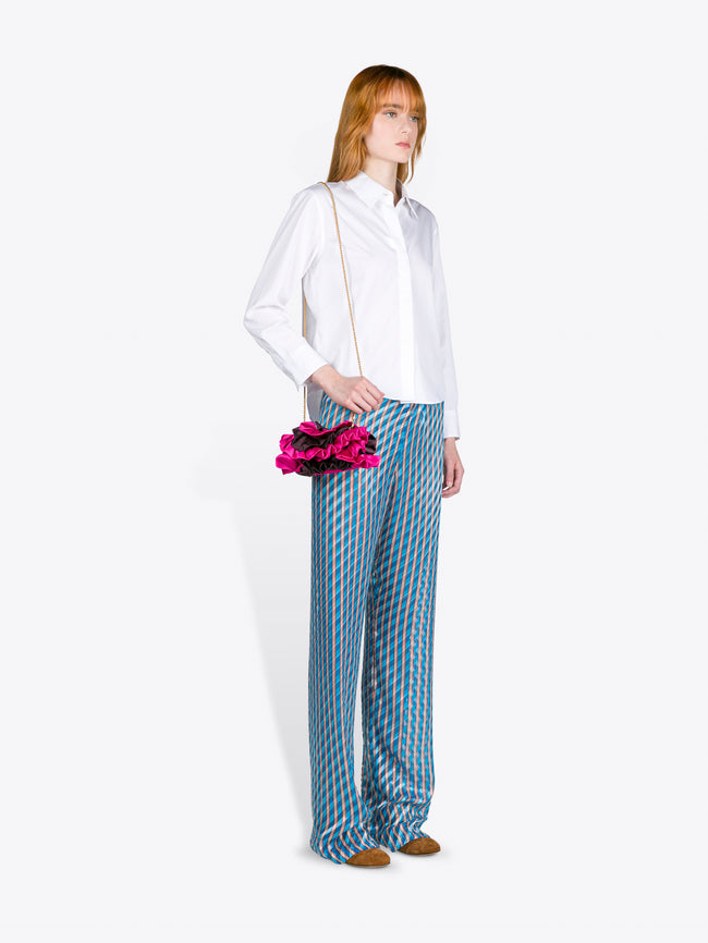 Woman wearing a white blouse and blue checkered pants holding pink flowers on a white background - Dries Van Noten