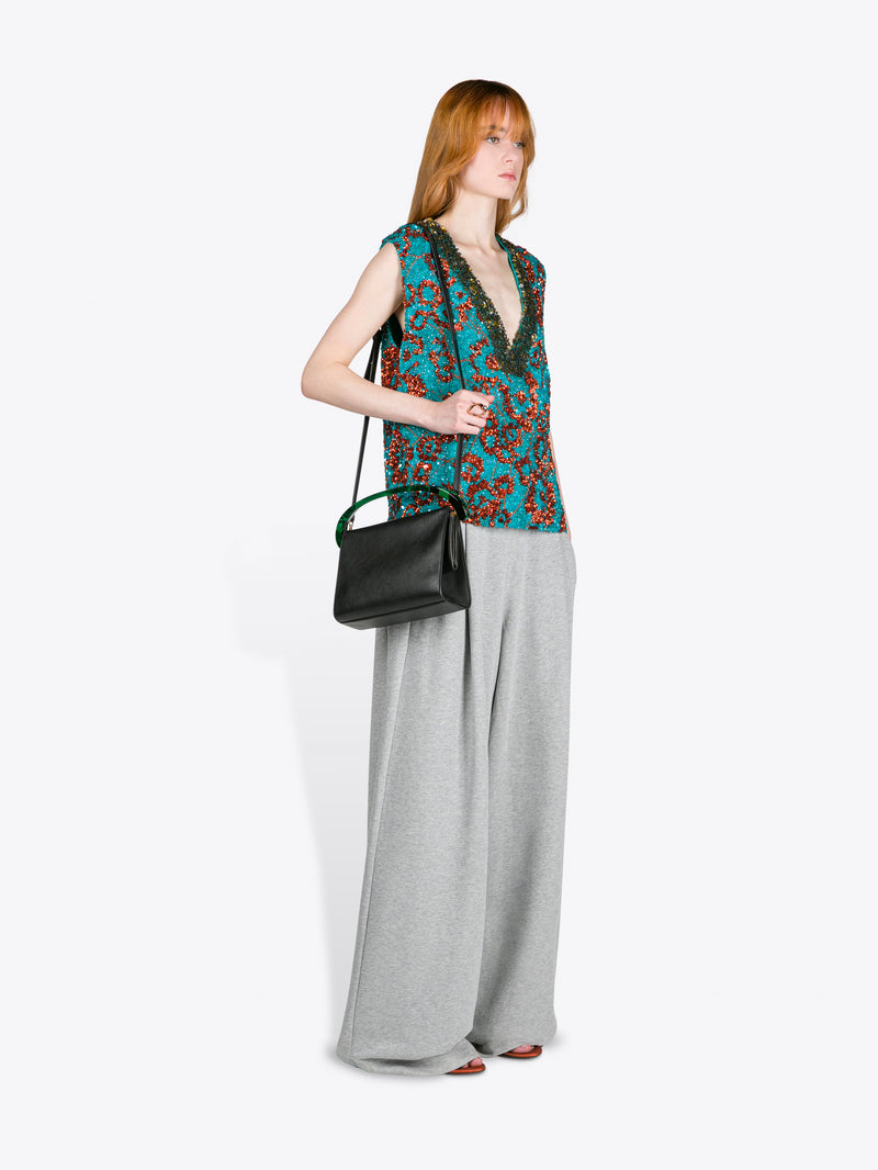 Woman wearing a patterned top and gray pants holding a black handbag on a white background - Dries Van Noten