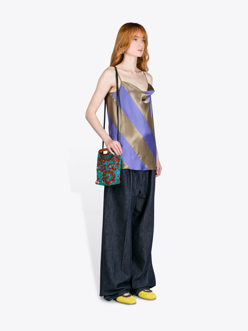 Woman wearing a colorful striped top and dark pants, holding a patterned handbag on a white background - Dries Van Noten