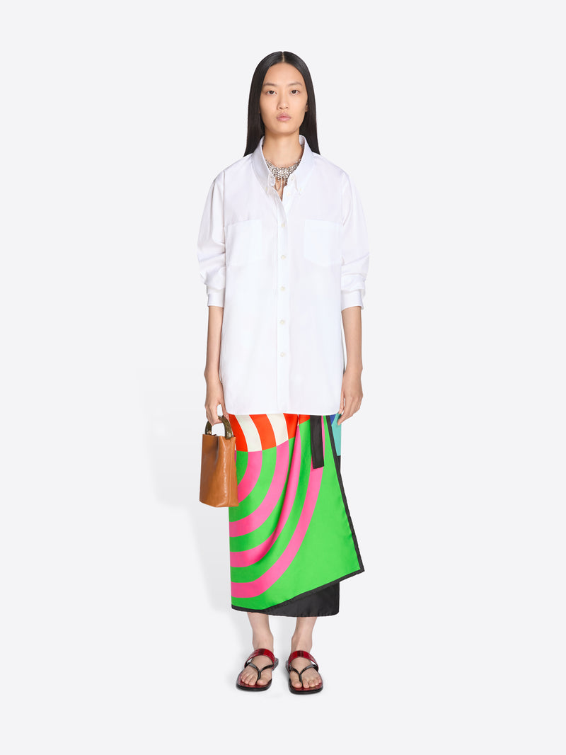 Woman wearing a white shirt and colorful skirt with a brown bag on a white background - Dries Van Noten