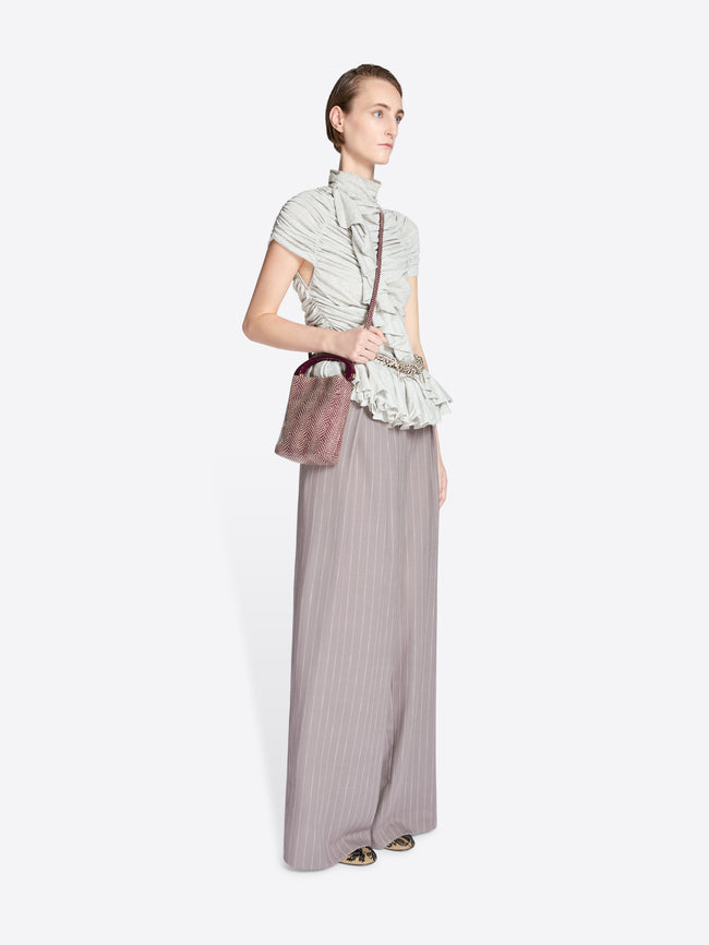 Woman wearing a patterned top and long skirt with a handbag on a white background - Dries Van Noten