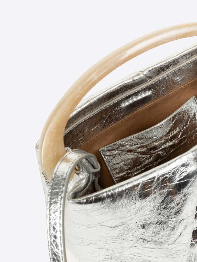 Close-up of a silver handbag with a beige handle on a white background