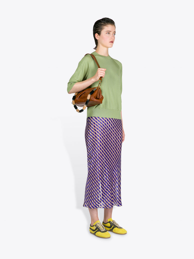 Woman wearing a green top and purple skirt with a brown bag on a white background - Dries Van Noten