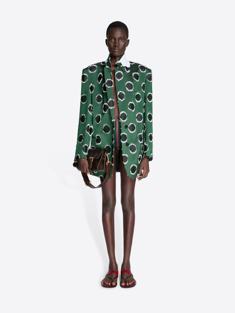 Model wearing a green patterned jacket with a white background - Dries Van Noten