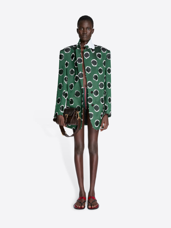 Model wearing a green patterned jacket with a white background - Dries Van Noten