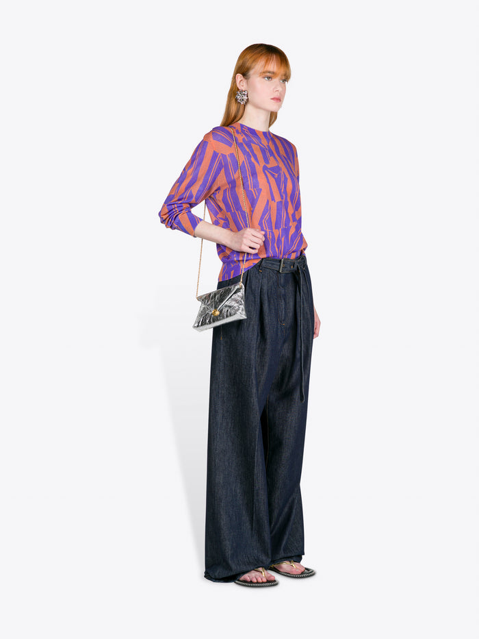 Woman wearing a patterned top and wide-leg pants holding a clutch against a white background - Dries Van Noten