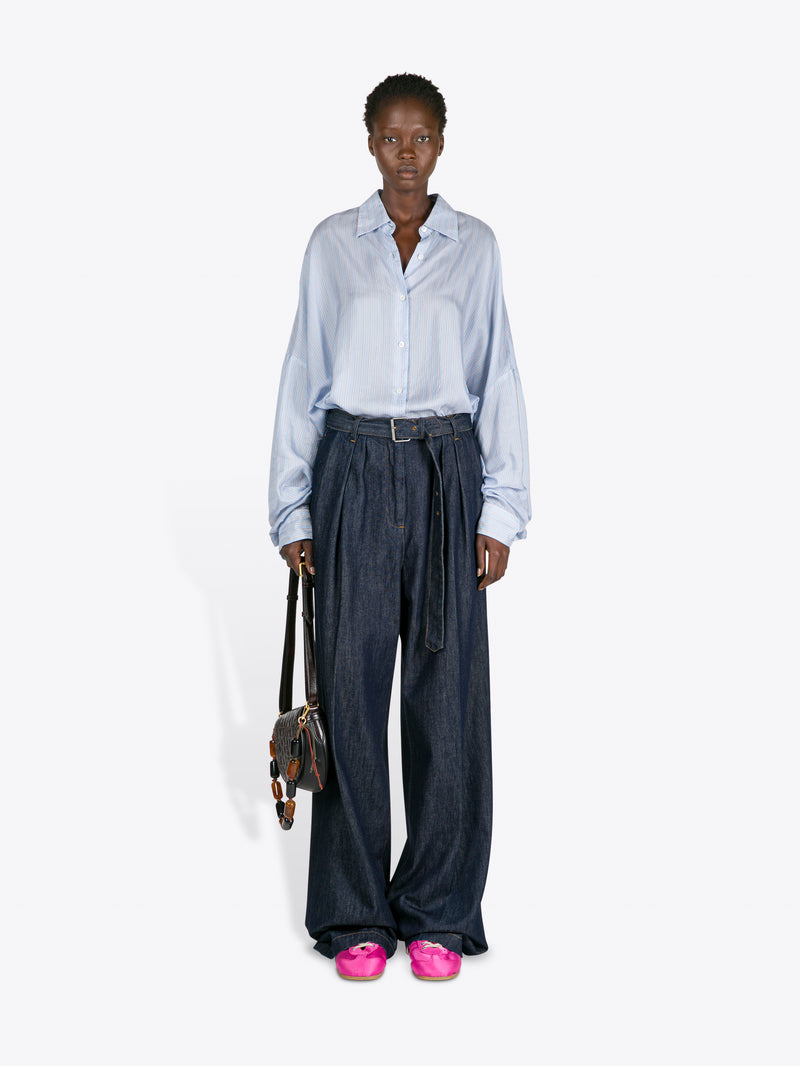 Person wearing a light blue shirt and dark pants with pink shoes on a white background - Dries Van Noten