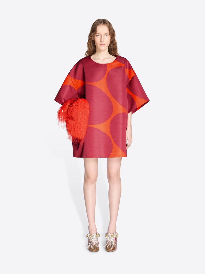 Model wearing a red and orange patterned dress with a white background - Dries Van Noten
