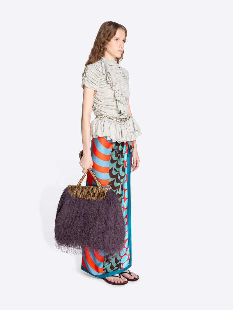 Woman holding a dark handbag wearing a patterned outfit on a white background - Dries Van Noten