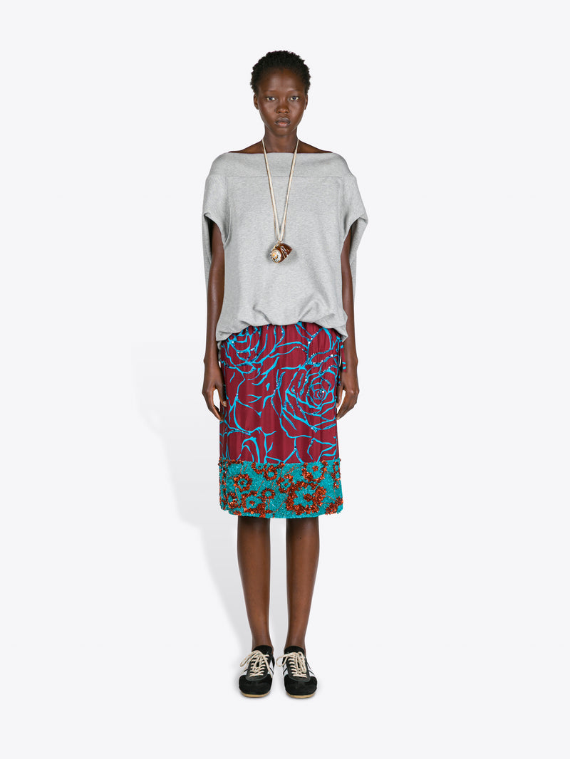 Model wearing a gray top and colorful patterned skirt on a white background