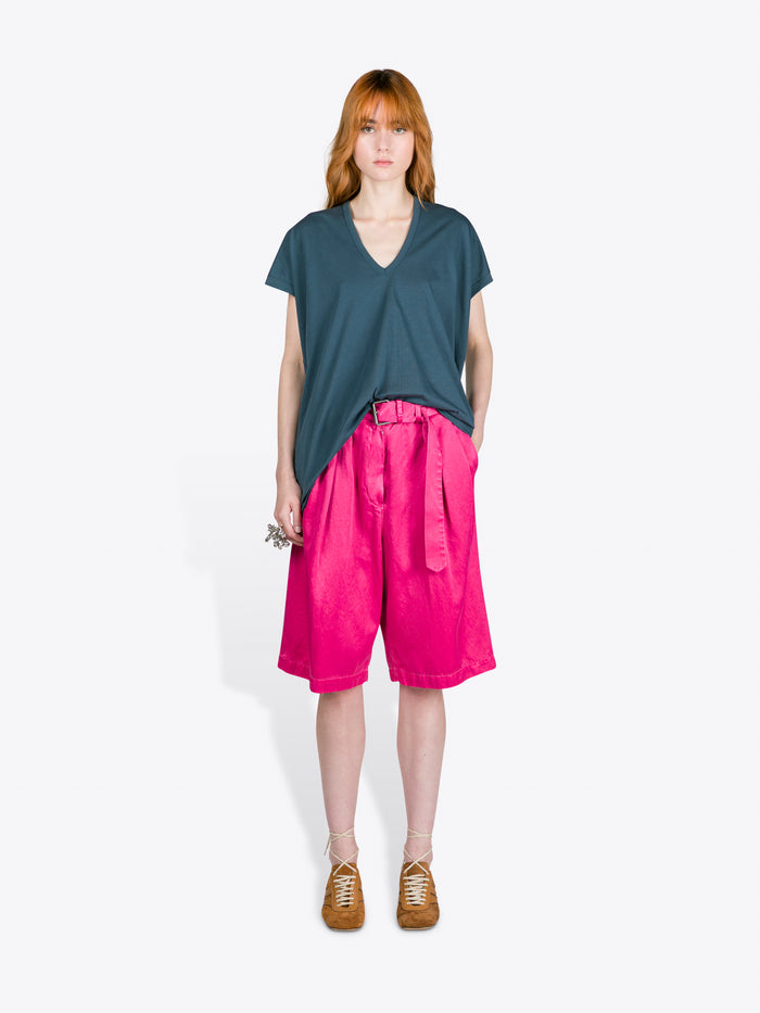 Person wearing a teal top and pink shorts on a white background