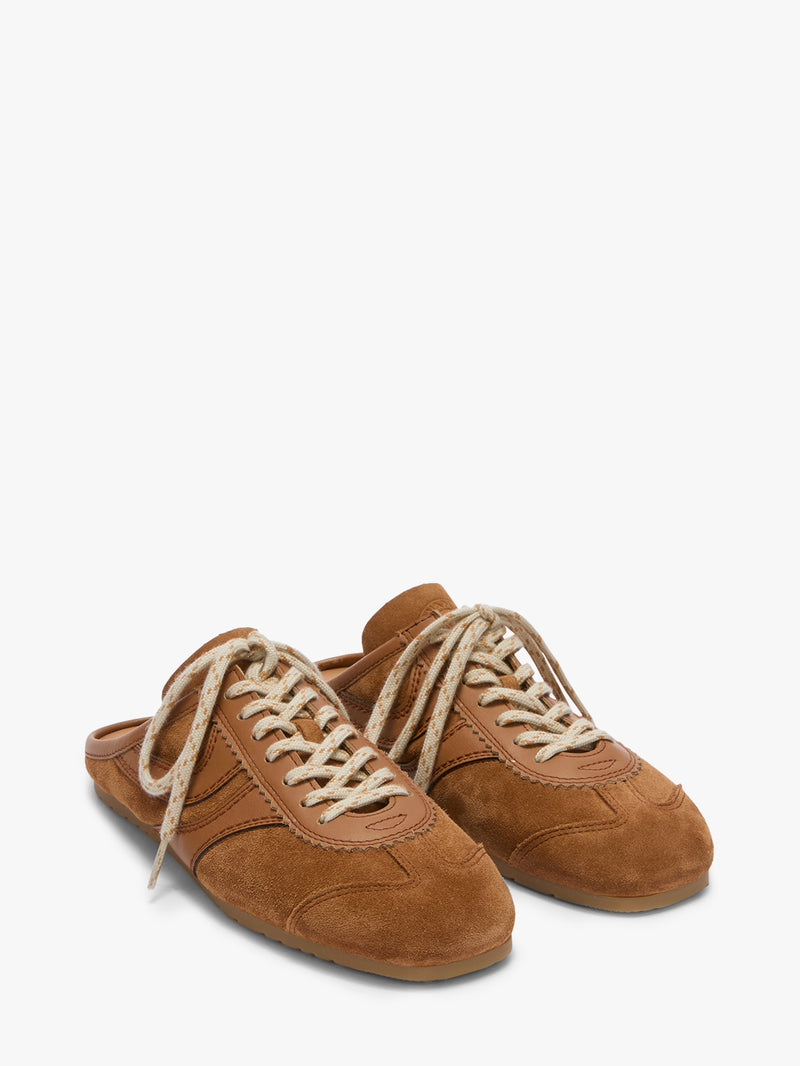 Pair of brown suede shoes with white laces on a white background
