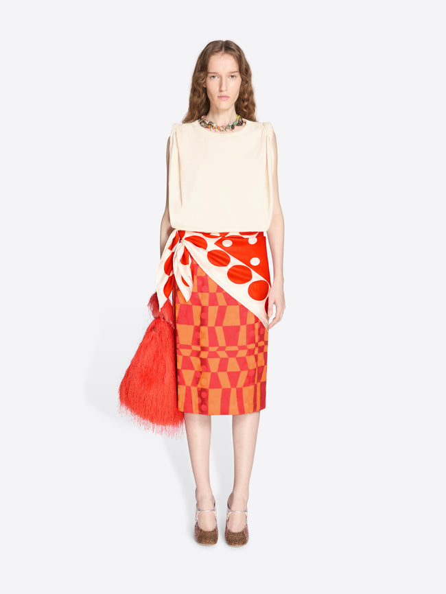 Woman wearing a cream top and red patterned skirt with a matching bag on a white background - Dries Van Noten