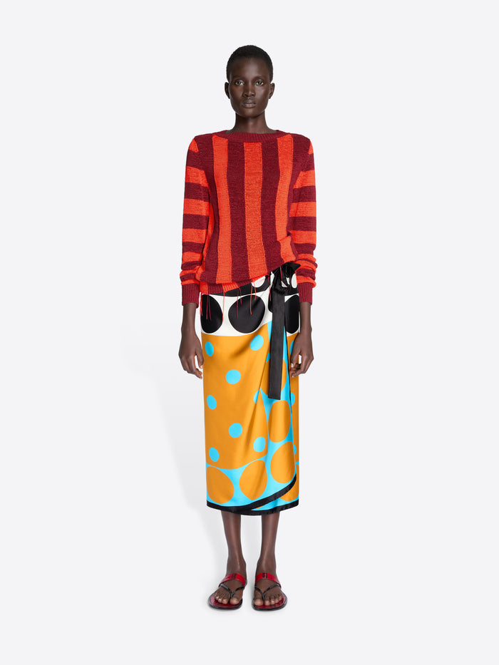 Model wearing a red and orange striped sweater with a colorful skirt on a white background - Dries Van Noten