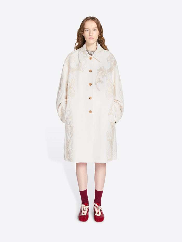 Person wearing a white coat on a white background - Dries Van Noten