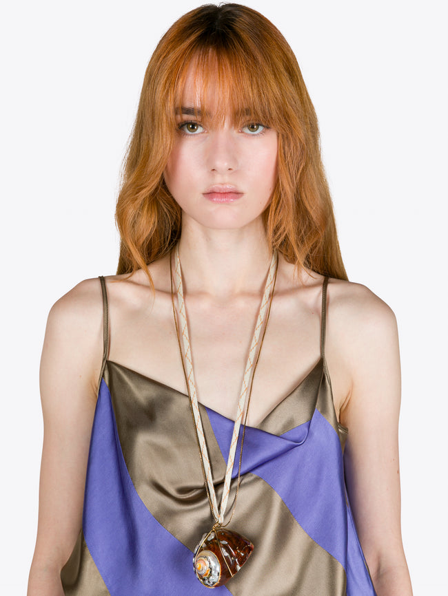 Woman wearing a colorful dress with a long necklace against a white background