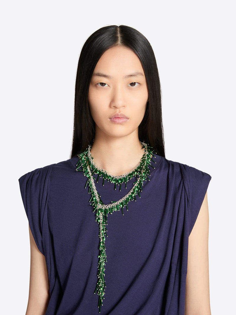 Woman wearing a dark blue top and green beaded necklace on a white background - Dries Van Noten