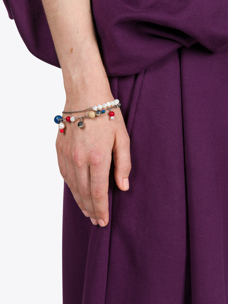 Hand wearing a colorful beaded bracelet on a purple fabric background