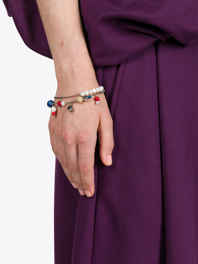 Hand wearing a colorful beaded bracelet on a purple fabric background