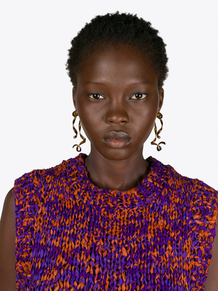 Woman wearing a purple and orange patterned top with gold earrings on a white background - Dries Van Noten