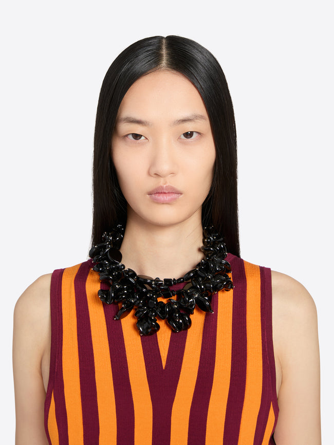Woman wearing a striped dress with a large black necklace on a white background - Dries Van Noten
