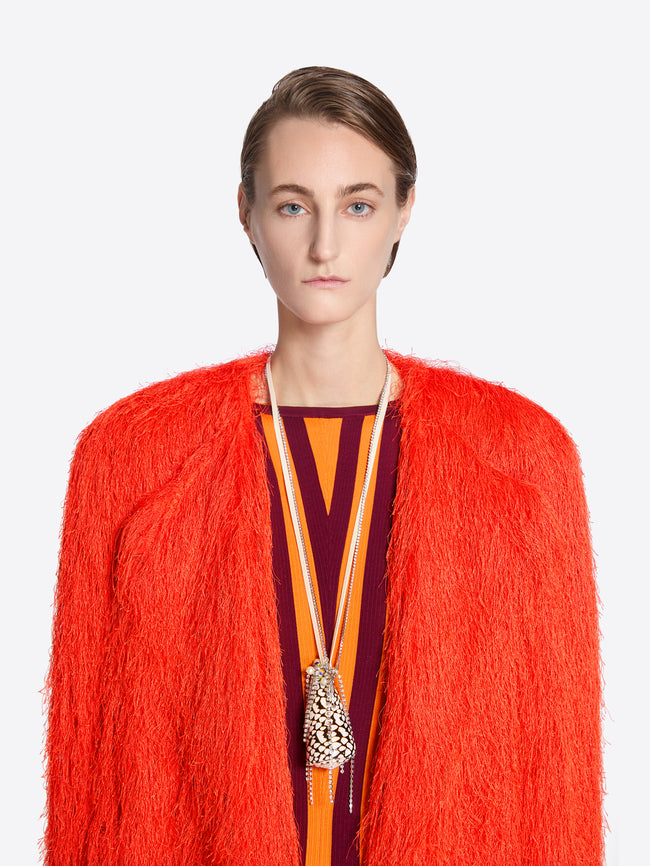 Person wearing a bright orange textured coat with a white background - Dries Van Noten