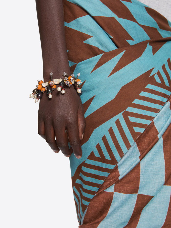 Hand wearing a bracelet with a patterned fabric background - Dries Van Noten