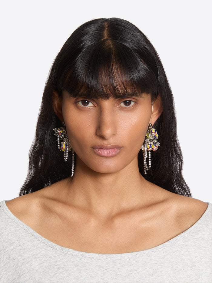 Woman wearing large, colorful earrings against a neutral background - Dries Van Noten